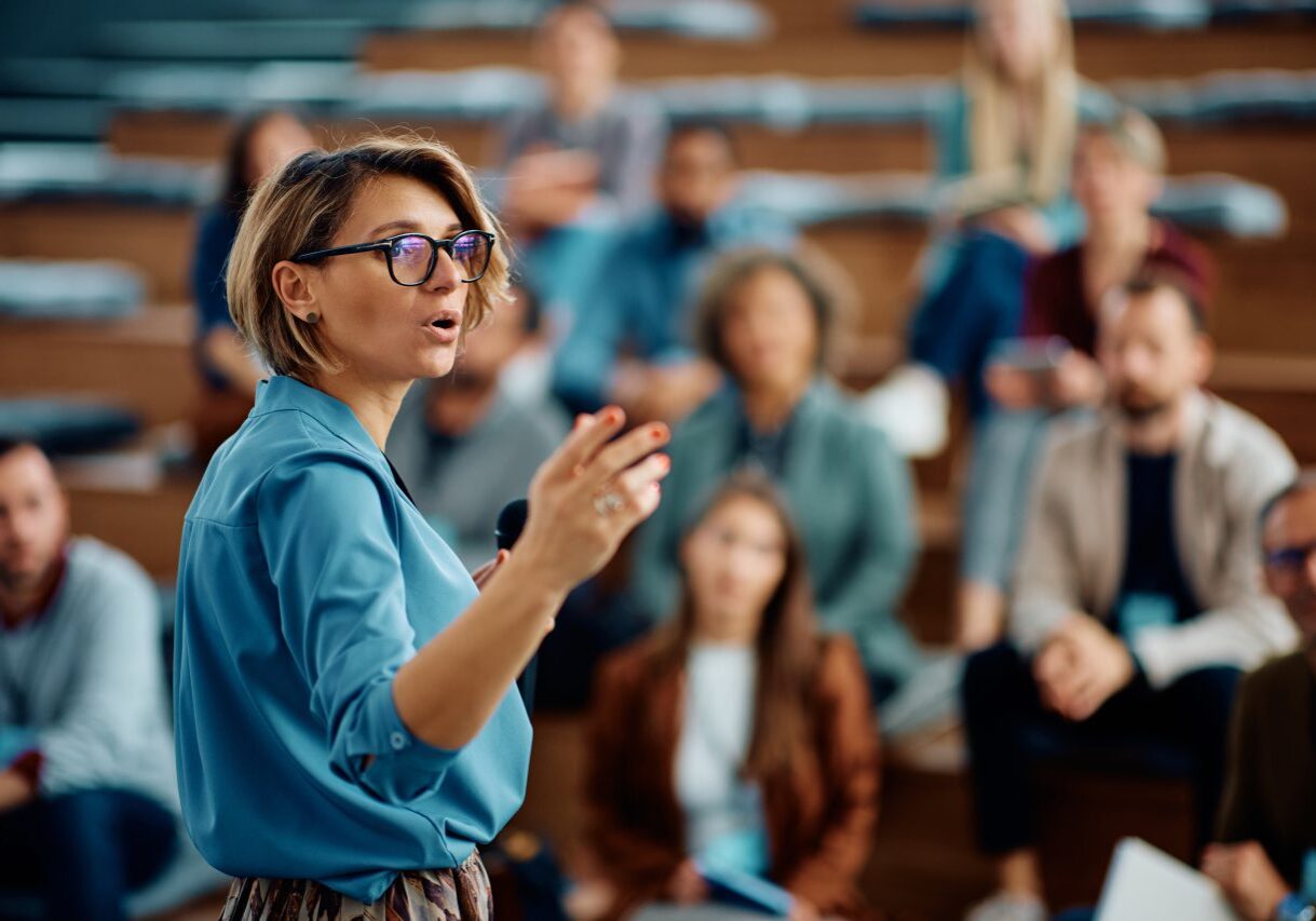 Speaker addressing audience in a lecture hall.